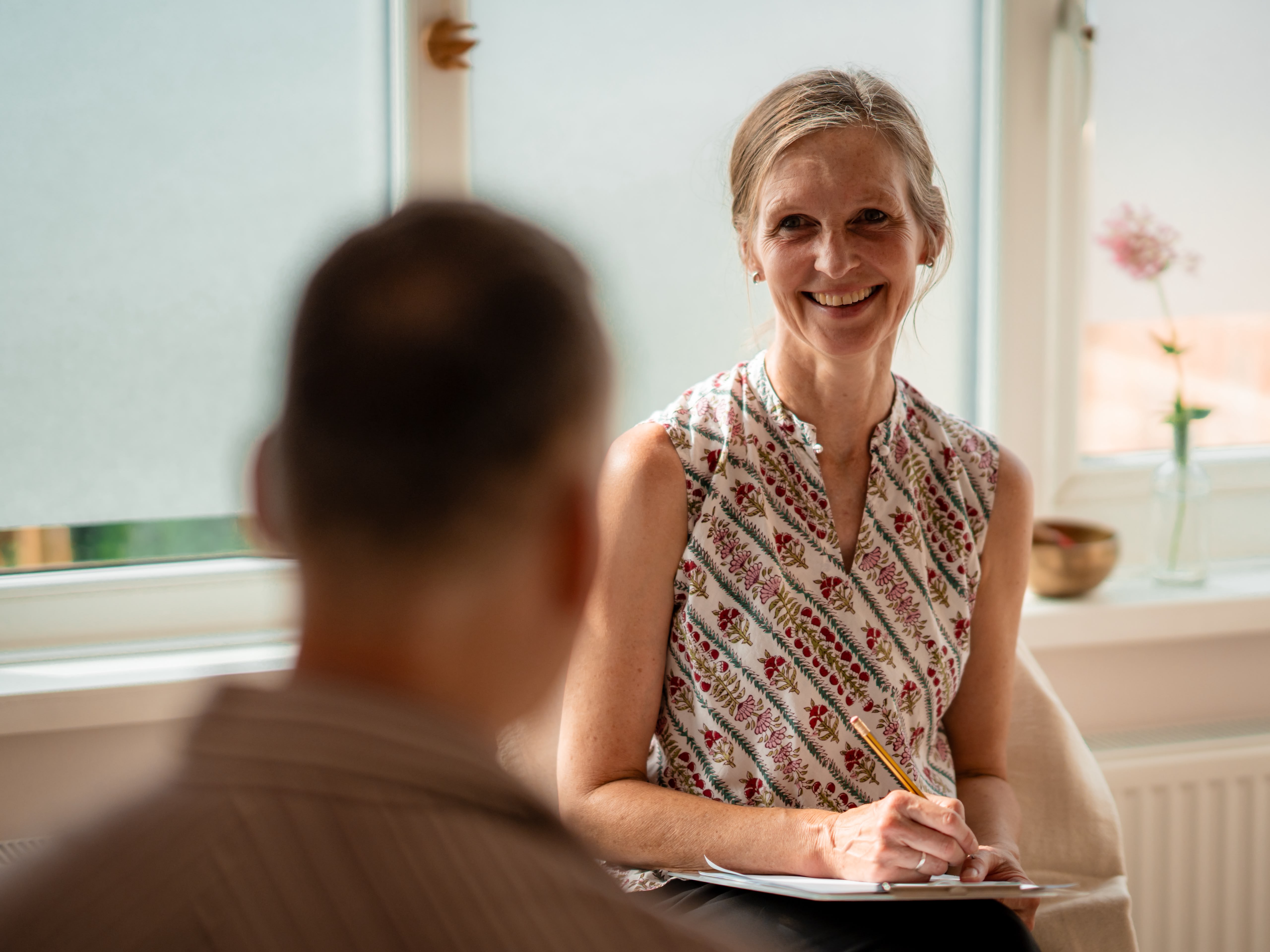 Wiebke smiling while making notes during a yoga therapy consultation