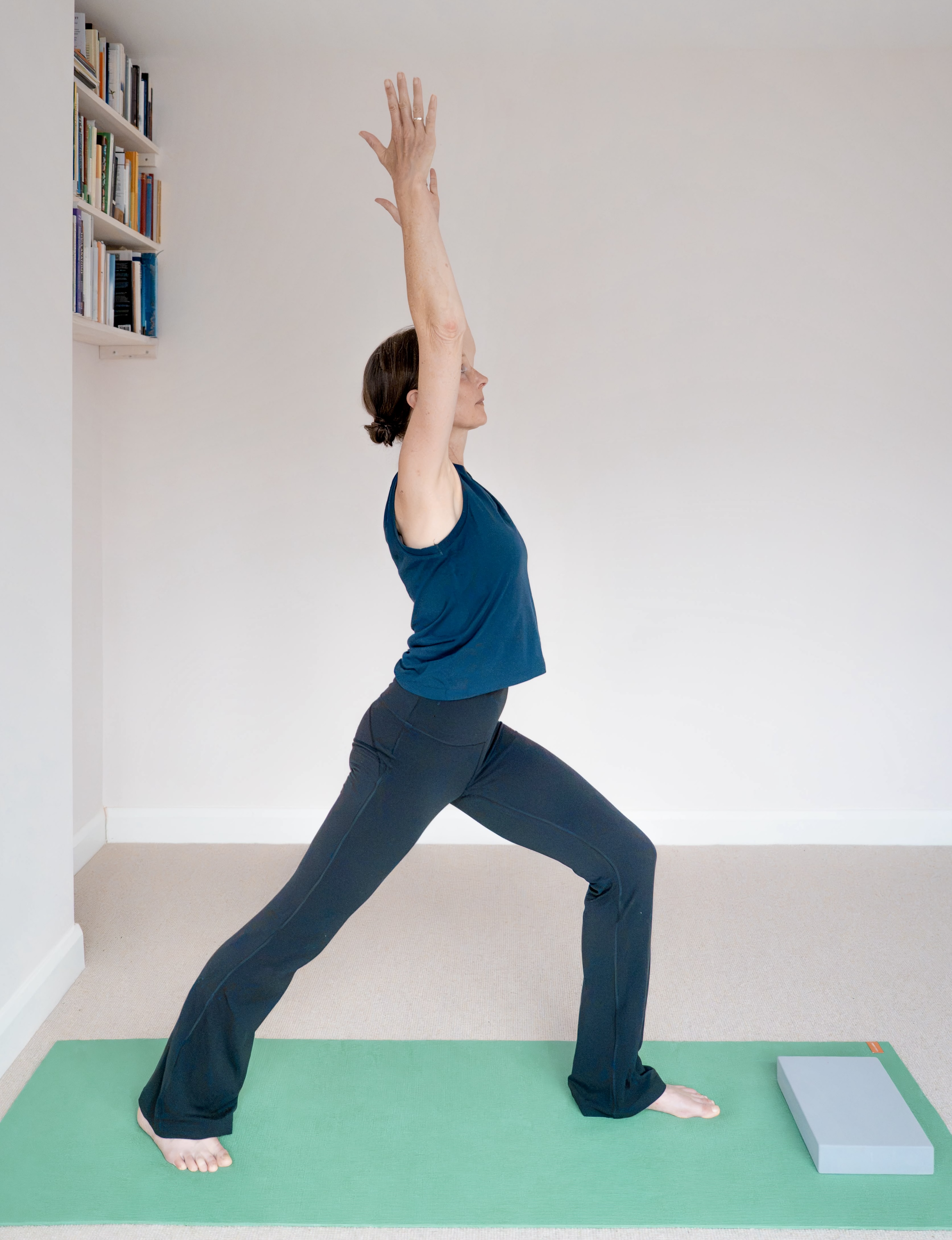 Wiebke reaching up in warrior pose during a home practice